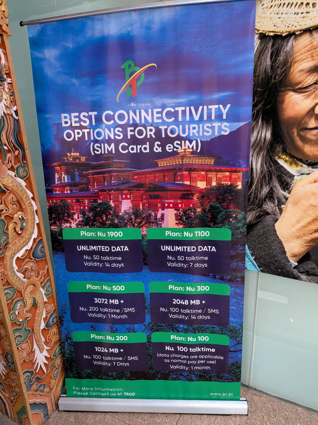 Panneau de prix SIM et eSIM touriste de Bhutan Telecom (BT) à l'aéroport de Paro, photographié en octobre 2026, listant six paliers de prix de Nu. 100 à Nu. 1900
